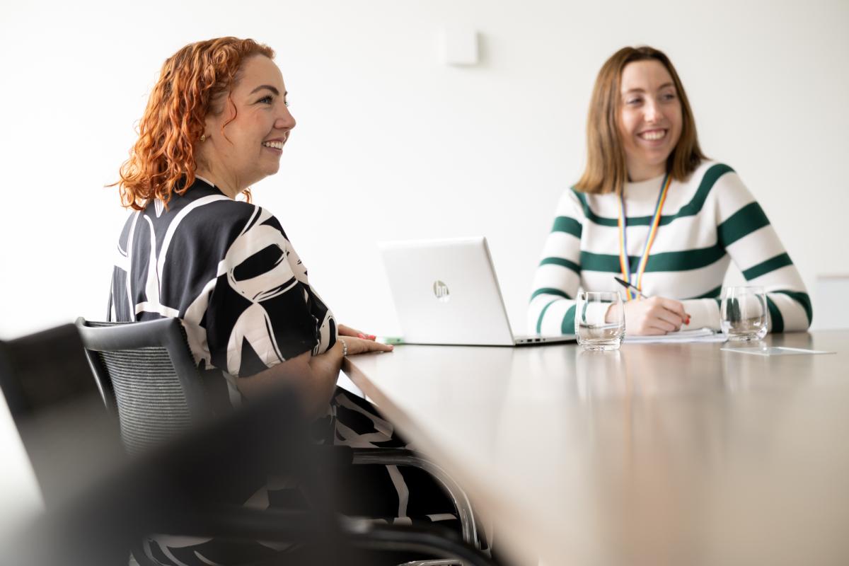 Two women sitting across from one another. One woman has a laptop in front of her.
